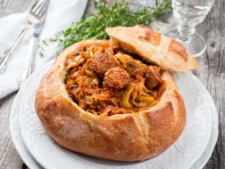 Bigos staropolski w chlebie, sycące danie z kapusty i kiełbasy, idealne na zimowe wieczory.