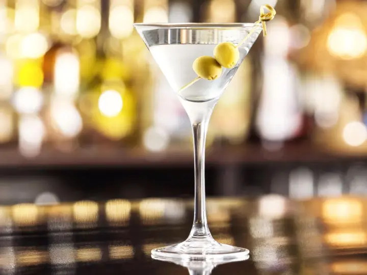 Elegancki gin z wermutem, ozdobiony dwiema oliwkami, czeka na Ciebie przy barze.