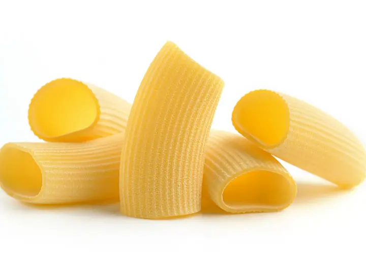 Kilka kawałków makaronu rigatoni, z charakterystycznymi rowkami, gotowych do sosu.