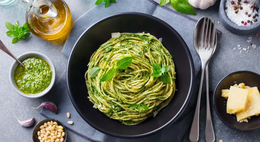 Pyszne spaghetti z pesto, idealne co na obiad zamiast mięsa. Podane z parmezanem, orzeszkami pinii i świeżą bazylią.