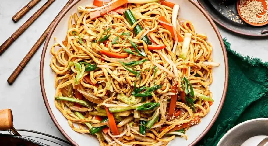 Pyszny makaron chow mein z warzywami i sezamem, gotowy do jedzenia pałeczkami.