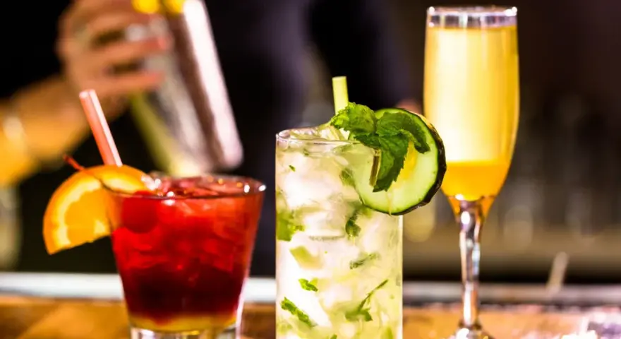 Mojito na białym rumie kontra Mojito na ciemnym. Trzy drinki: czerwony z pomarańczą, zielony z ogórkiem i żółty.