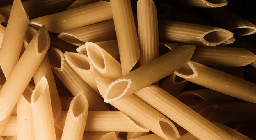 Stos makaronu penne, czy to orkiszowy czy żytni, czeka na gotowanie.