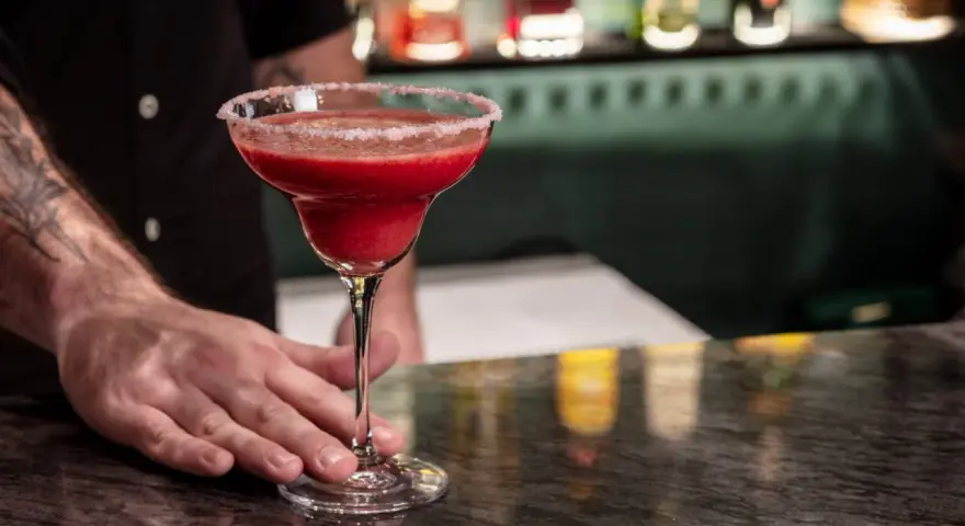 Margarita klasyczna kontra Margarita truskawkowa. Barman podaje orzeźwiającą, mrożoną truskawkową Margaritę z solą na brzegu kieliszka.