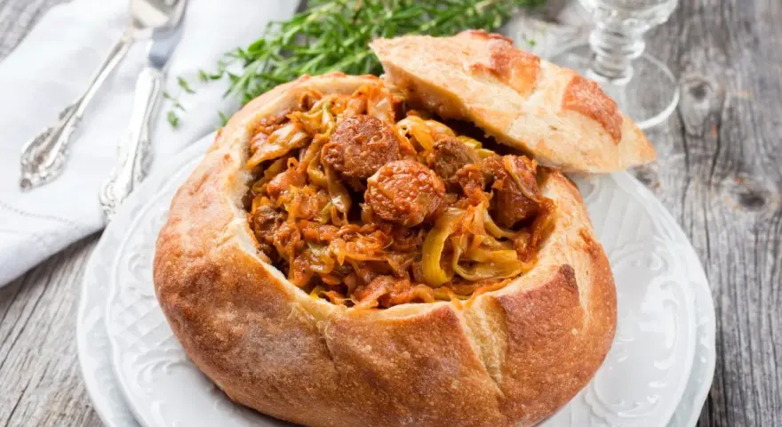 Bigos staropolski w chlebie, sycące danie z kapusty i kiełbasy, idealne na zimowe wieczory.
