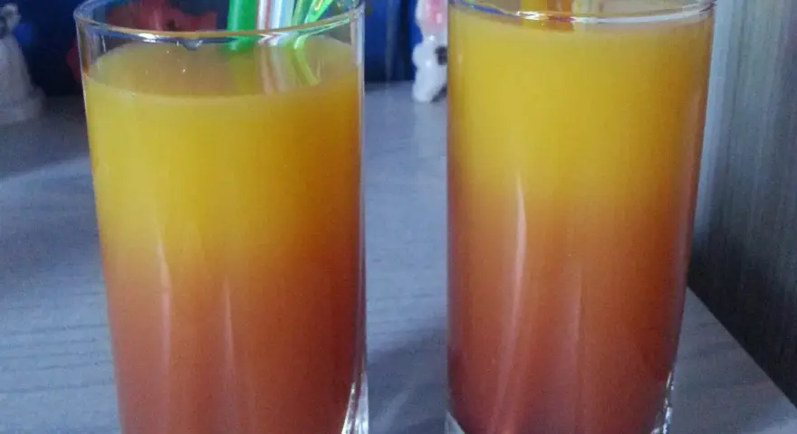 Dwa orzeźwiające drinki z sokiem malinowym, tworzące piękny gradient od czerwieni do żółci, gotowe do degustacji.
