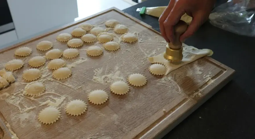 Ravioli z ricottą i szpinakiem przepis: ręcznie robione pierożki na desce, posypane mąką.