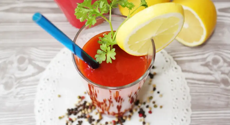 Orzeźwiający drink z sokiem pomidorowym, ozdobiony plasterkiem cytryny i natką pietruszki, gotowy do wypicia.