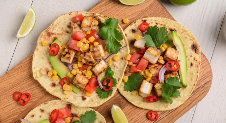 Zdrowy obiad dietetyczny: tortille z grillowanym tofu, kukurydzą, pomidorami, awokado i kolendrą.