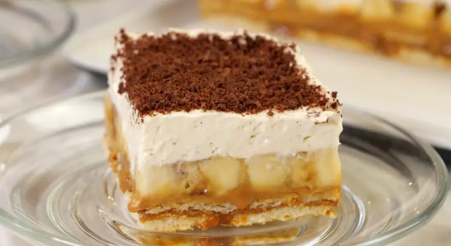Pyszny kawałek Banoffee Pie z bananami, karmelem i bitą śmietaną, posypany czekoladą. Idealny przepis na deser.