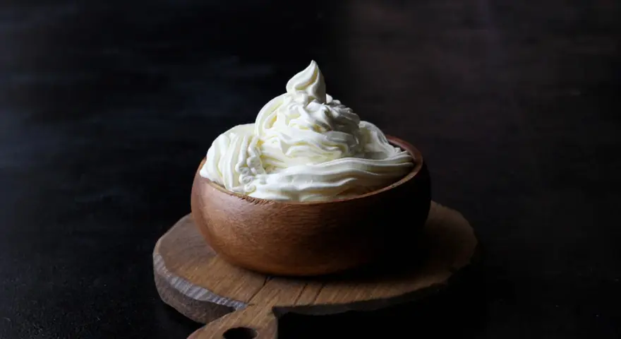 Kremowa masa w drewnianej miseczce, idealna do deserów. Mascarpone kontra serek homogenizowany – który wybierzesz?