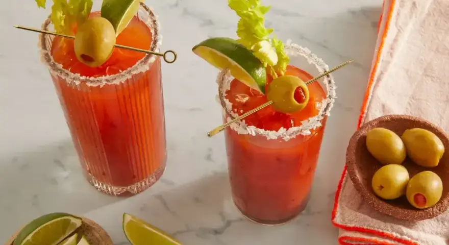 Dwa Bloody Mary: jedno na soku pomidorowym, drugie na passacie. Oba ozdobione łodygą selera, limonką i oliwką.