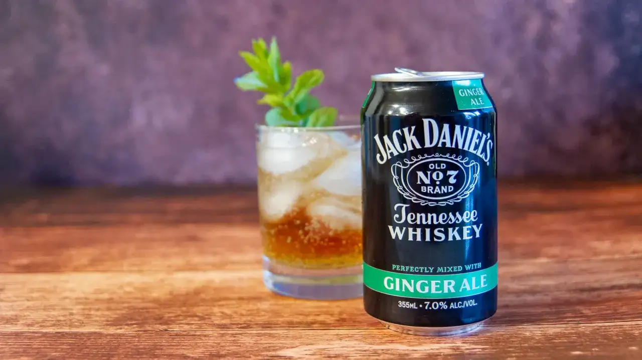 Whiskey z colą kontra Whiskey z ginger ale. Puszka Jack Daniel's Tennessee Whiskey z dodatkiem ginger ale obok szklanki z lodem i miętą.
