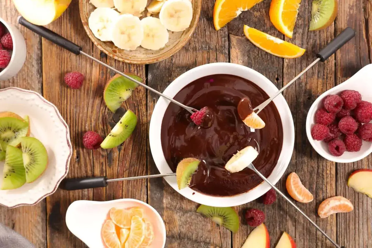 Jak zrobić fondue czekoladowe? Zanurz owoce w gorącej czekoladzie. Maliny, kiwi, banany i mandarynki czekają na dip.