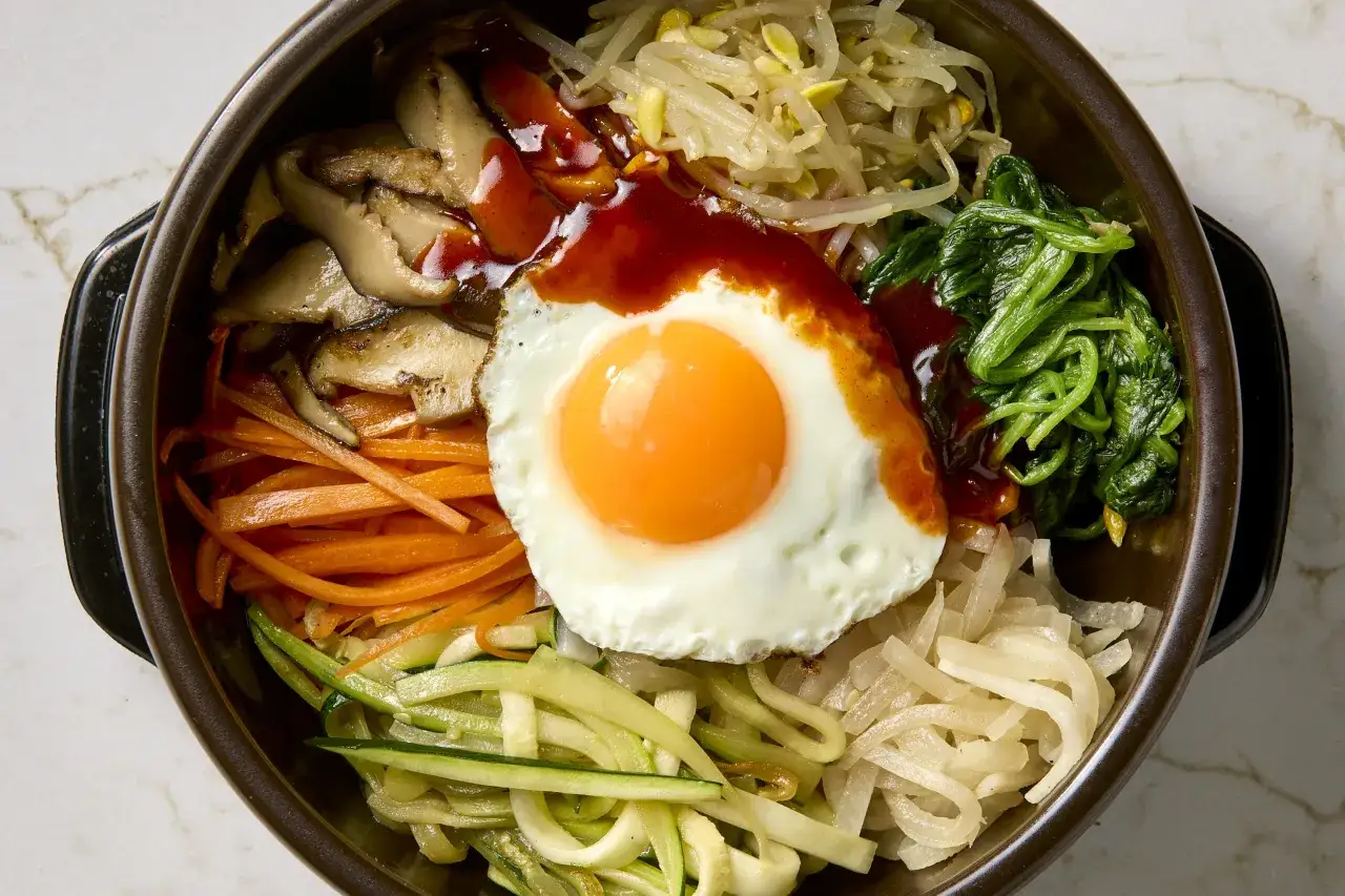Kolorowy bibimbap z jajkiem sadzonym, grzybami, marchewką, szpinakiem i kiełkami fasoli. Idealny przepis na szybki obiad.