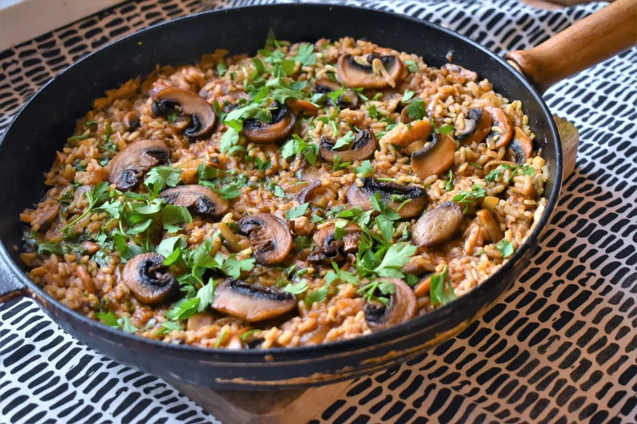 Aksamitne risotto z grzybami w czarnej patelni, pachnące ziołami. Czy to początek kulinarnego pojedynku z Paellą z owocami morza?