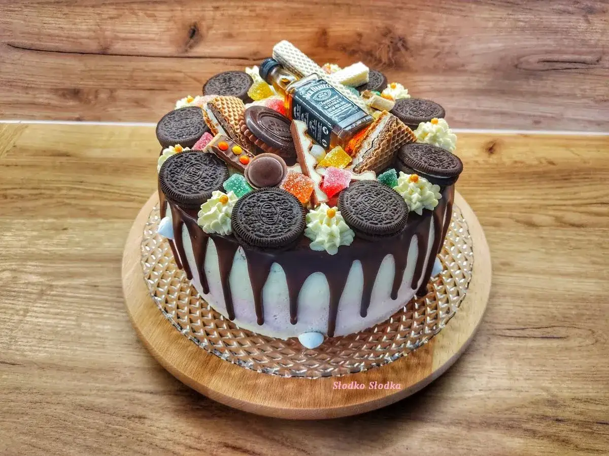Jak udekorować ciasto czekoladowe? Zobacz tort z polewą, ciasteczkami Oreo, batonikami i mini butelką Jack Daniel's.