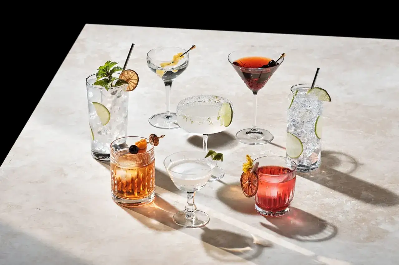 Różnorodne drinki, w tym klasyczny Bacardi, na kamiennym blacie, ozdobione owocami i ziołami.