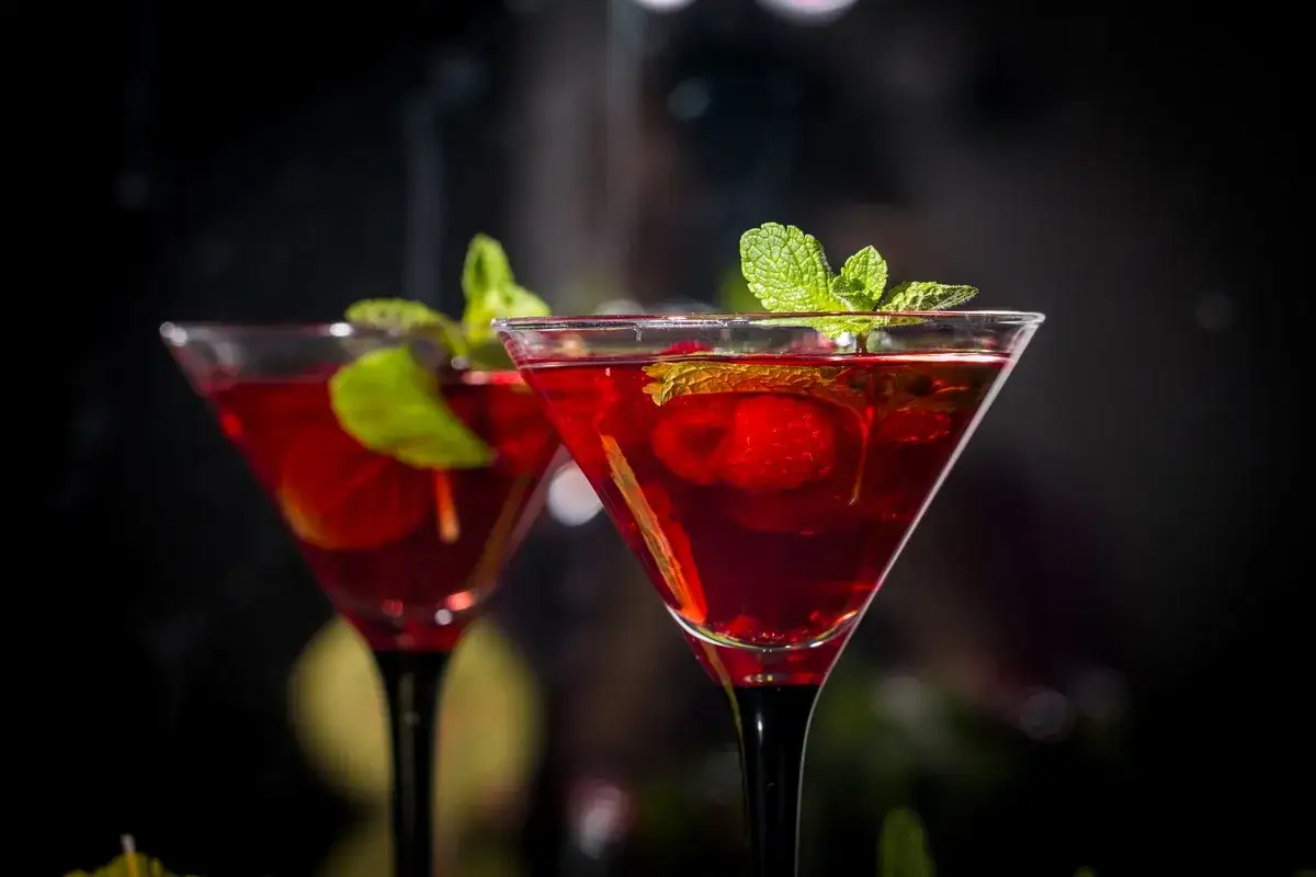 Dwa eleganckie drinki z piwem garage, ozdobione miętą i truskawkami, kuszą głębokim, rubinowym kolorem.