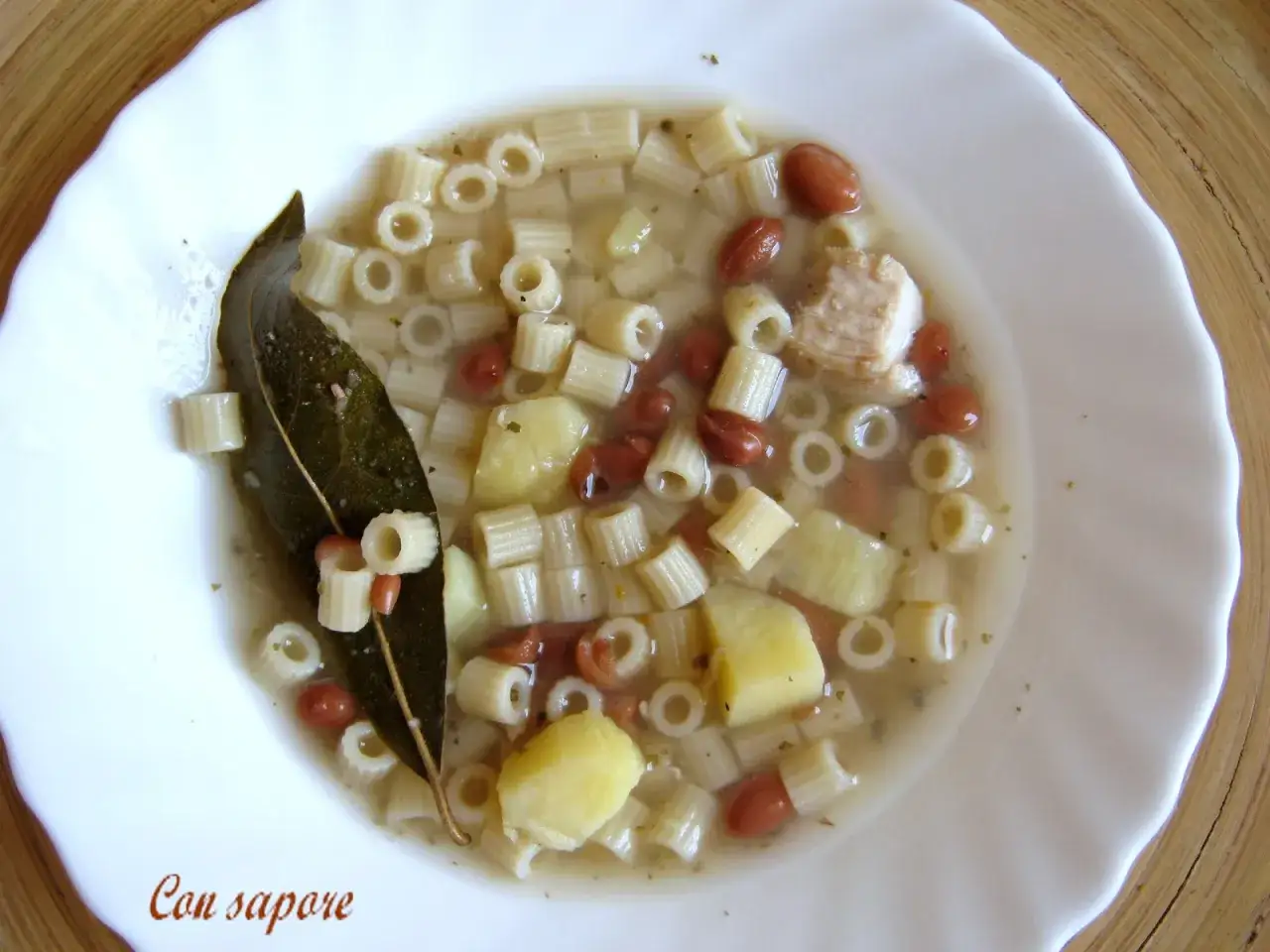 Zupa z makaronem ditalini, fasolą, ziemniakami i kawałkami kurczaka, ozdobiona liściem laurowym.