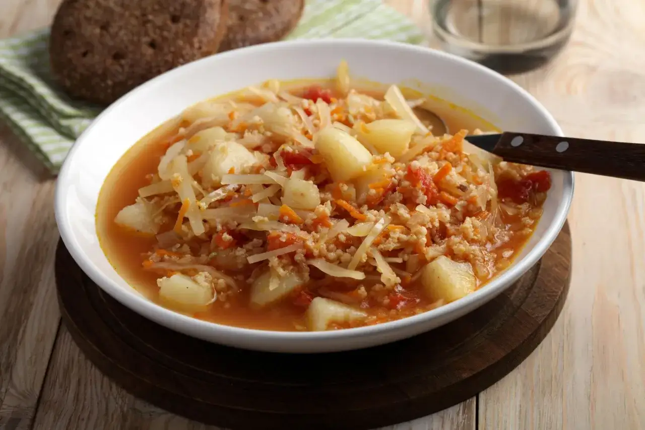 Gęsty kapuśniak ze świeżej kapusty z ziemniakami i marchewką, podany z chlebem. Pyszna kwaśnica na obiad.
