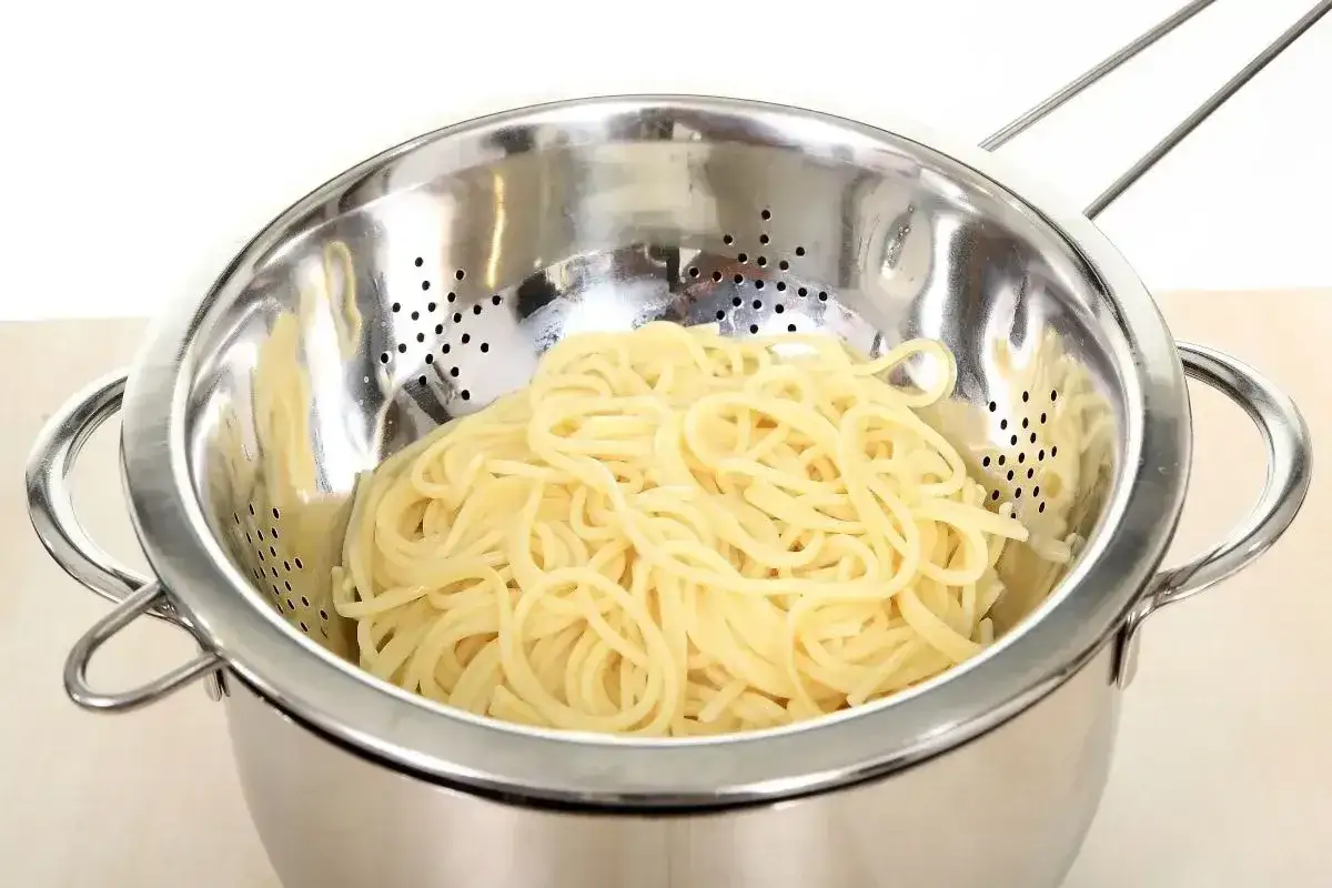 Ugotowany makaron spaghetti w durszlaku. Dowiedz się, jak przechowywać ugotowany makaron, aby był świeży i gotowy do użycia.
