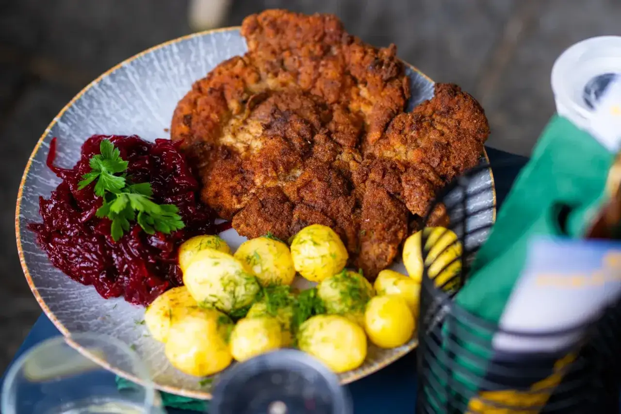 Kotlet schabowy czy kotlet z piersi kurczaka? Na talerzu złocisty kotlet, ziemniaczki i czerwona surówka.