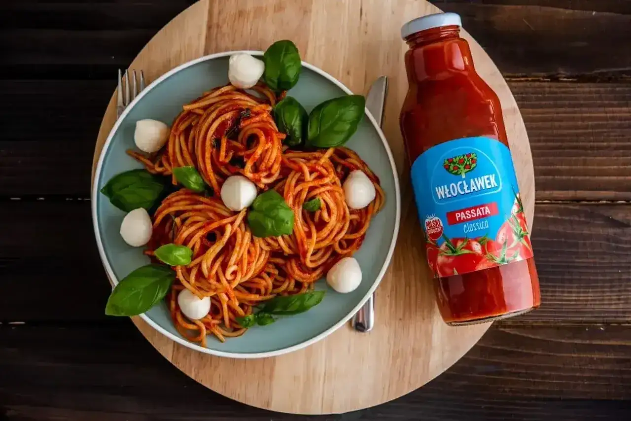 Pyszne spaghetti z passatą pomidorową Włocławek, ozdobione kulkami mozzarelli i bazylią. Idealny obiad z polskim akcentem.