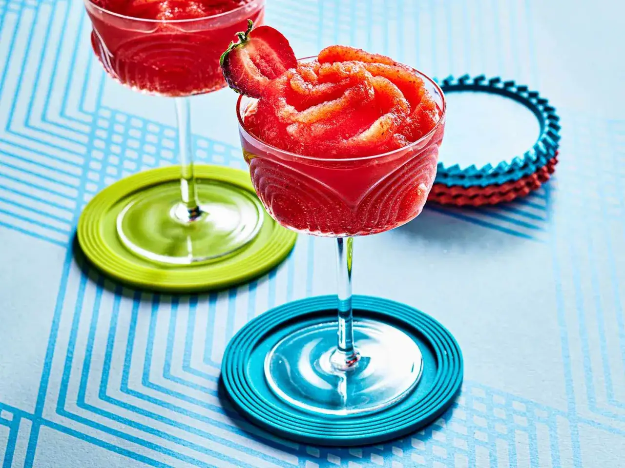 Orzeźwiający strawberry daiquiri, udekorowany plasterkiem truskawki, na kolorowych podkładkach. Idealny na letnie popołudnie.