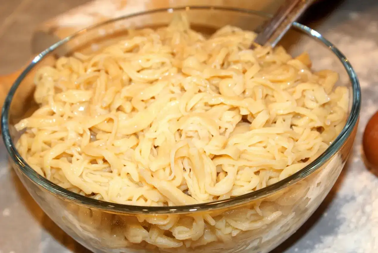 Miseczka pełna domowego makaronu jajecznego do zup, gotowego do podania. W przeciwieństwie do makaronu instant, ten jest pyszny i sycący.