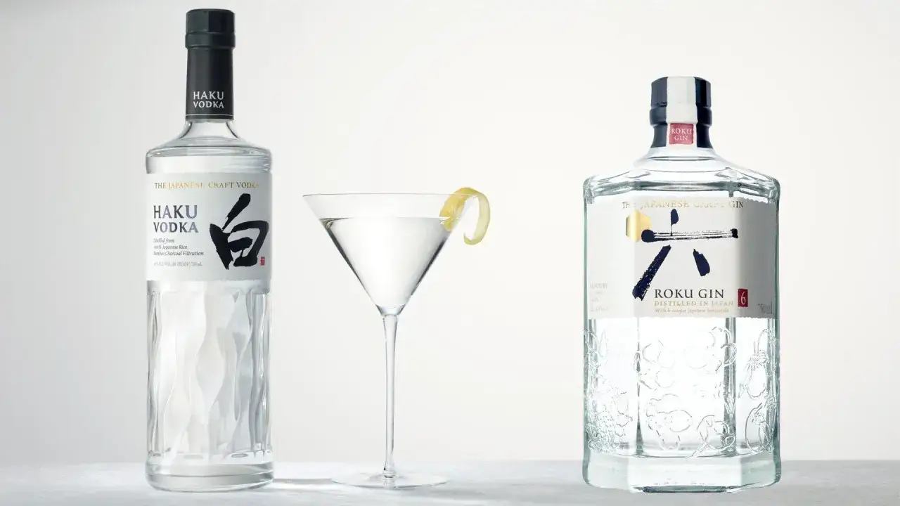 Elegancki drink z wódką Haku i drink z ginem Roku, oba japońskie, stoją obok kieliszka martini z cytrynową skórką.