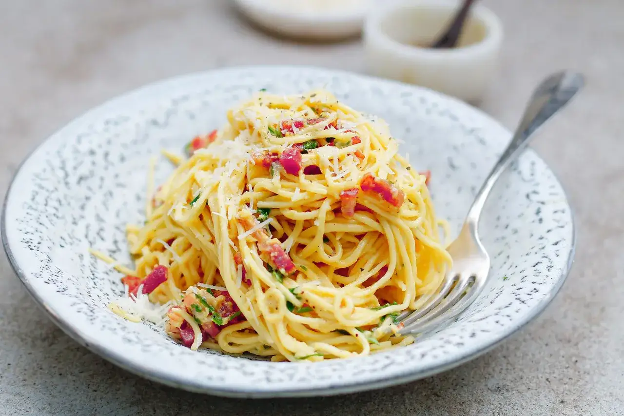 Pyszne spaghetti carbonara ze śmietaną, posypane parmezanem i kawałkami boczku. Idealne na szybki obiad.