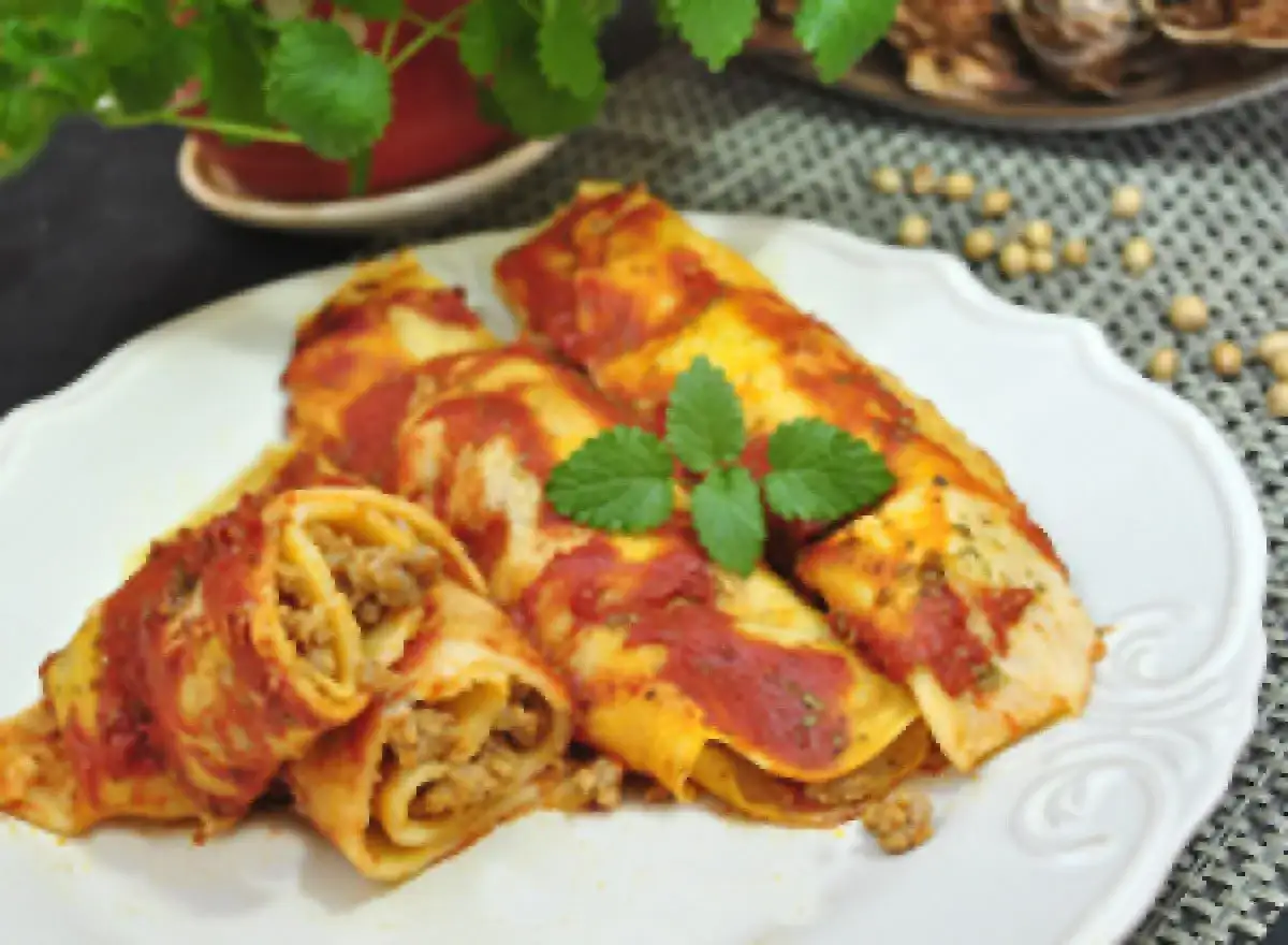 Cannelloni kontra naleśniki z mięsem: danie z makaronu lub naleśników, polane sosem pomidorowym, udekorowane miętą.