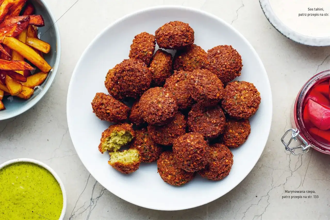 Falafel kontra kotlety sojowe: chrupiące kulki z ciecierzycy na talerzu, obok frytki i zielony sos.