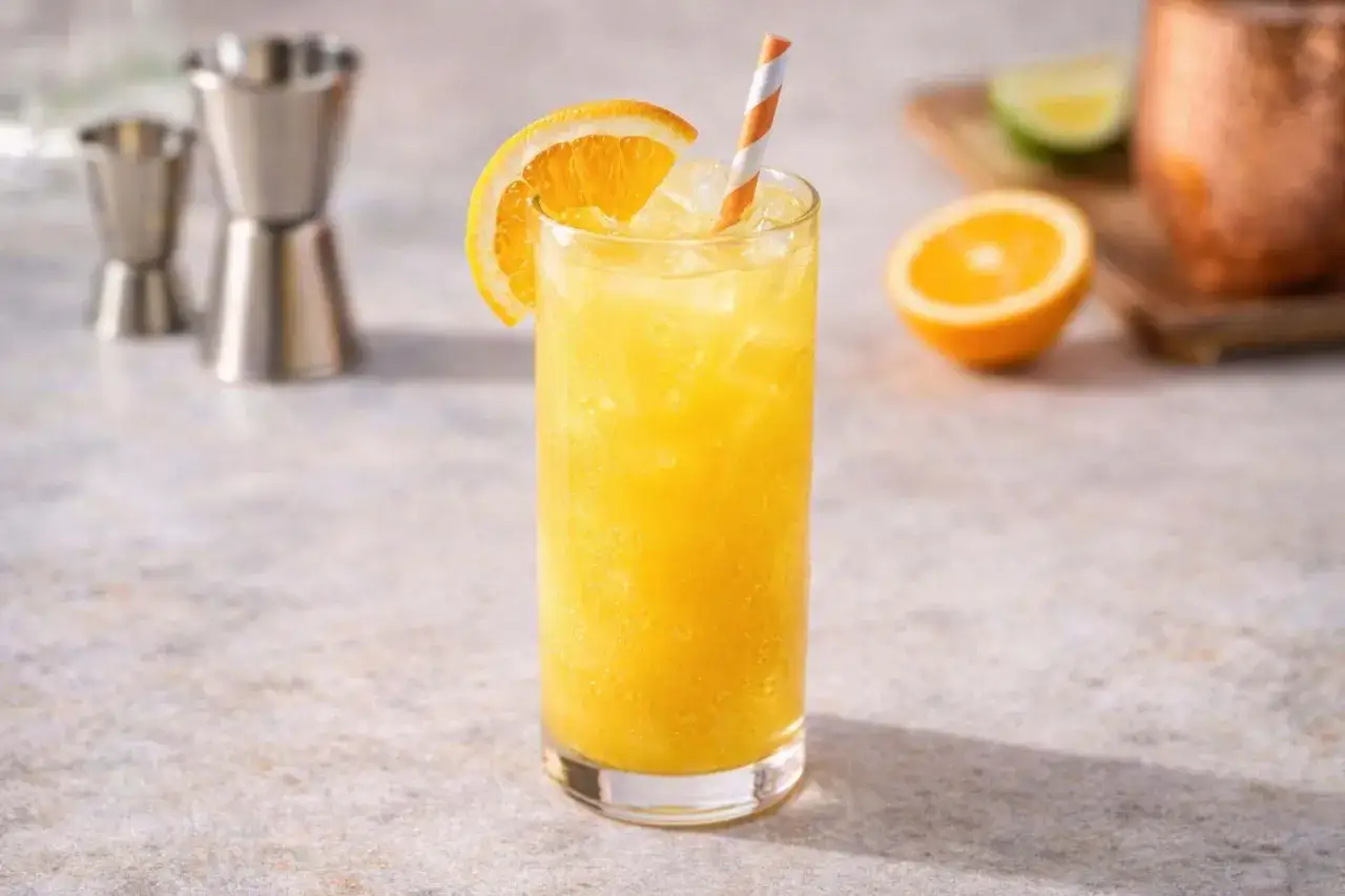 Orzeźwiający drink z wódką i sokiem pomarańczowym, udekorowany plasterkiem pomarańczy i kolorową słomką.