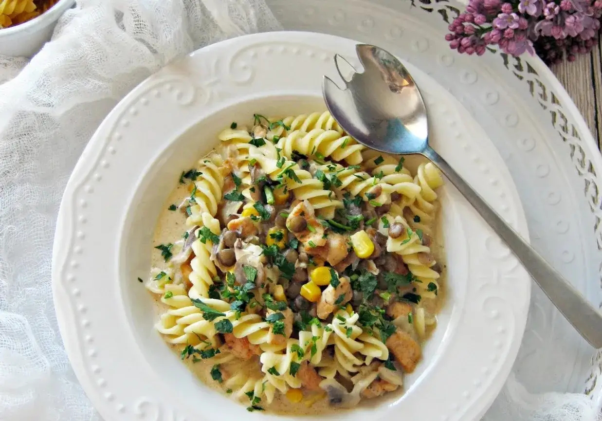 Tani obiad za 10 zł: makaron fusilli z kurczakiem, soczewicą, kukurydzą i pieczarkami w kremowym sosie, posypany natką pietruszki.