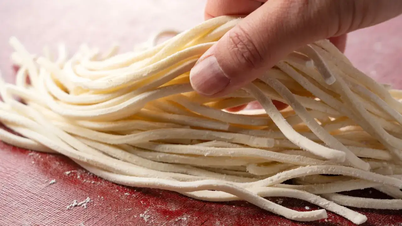 Dłoń trzymająca pęczek grubego makaronu udon. Czy to wersja mrożona czy suszona?