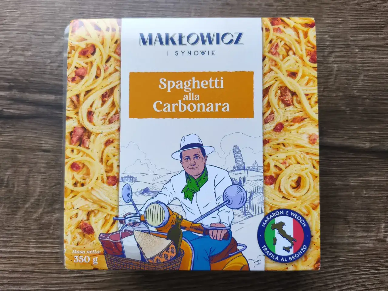 Gotowe spaghetti carbonara Makłowicz i Synowie. Na opakowaniu rysunek mężczyzny na skuterze z koszykiem pełnym włoskich produktów.