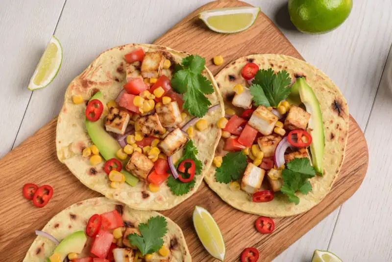Zdrowy obiad dietetyczny: tortille z grillowanym tofu, kukurydzą, pomidorami, awokado i kolendrą.